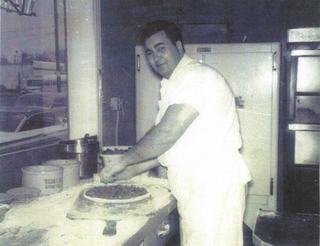 Poppie building a pizza by hand in the Art's kitchen.